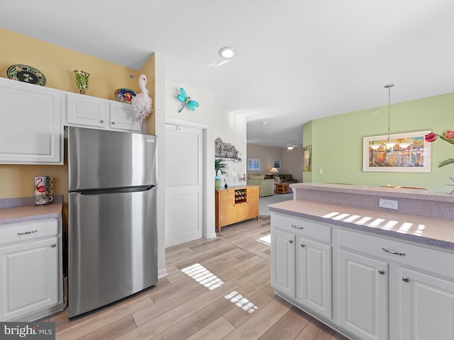 kitchen with white cabinetry, freestanding refrigerator, wood finish floors, and light countertops