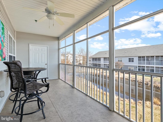 sunroom with a residential view and a ceiling fan