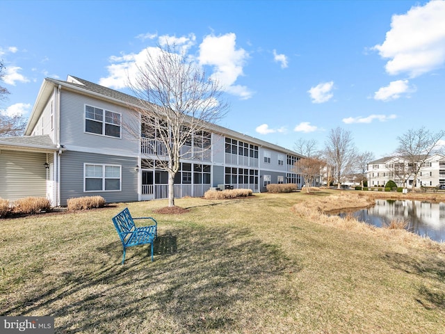 rear view of property featuring a water view and a lawn