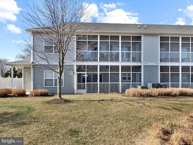 back of house featuring a lawn and a sunroom