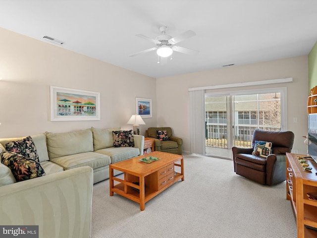 living area featuring ceiling fan, visible vents, and light carpet