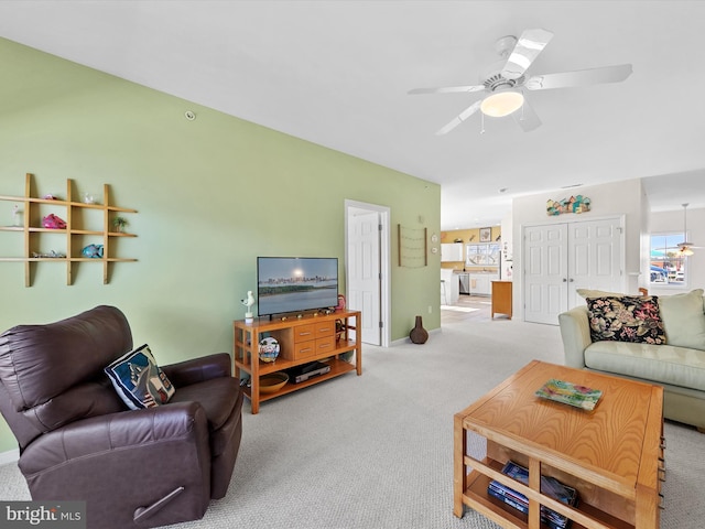 carpeted living area with baseboards and a ceiling fan