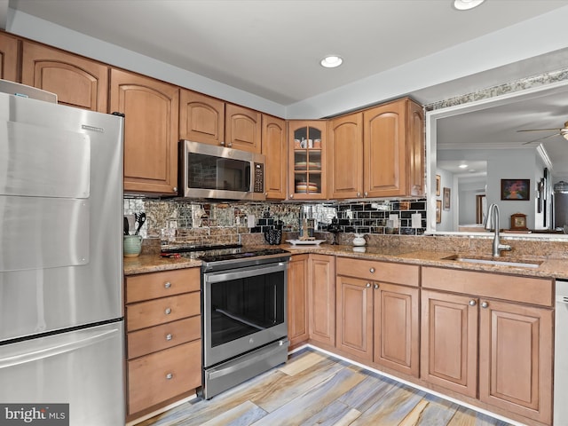 kitchen with a sink, tasteful backsplash, appliances with stainless steel finishes, glass insert cabinets, and light stone countertops