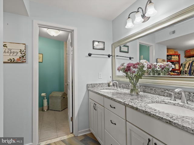 full bathroom with a sink, visible vents, baseboards, and double vanity