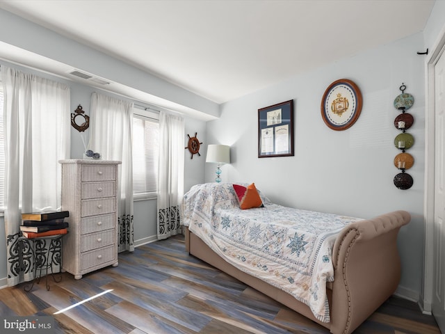 bedroom featuring visible vents, baseboards, and wood finished floors