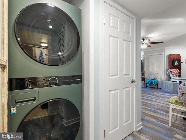 laundry area featuring a ceiling fan, wood finished floors, laundry area, ornamental molding, and stacked washer and dryer