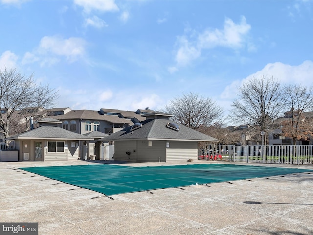 community pool with a patio area and fence