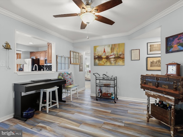 sitting room featuring baseboards, wood finished floors, and crown molding