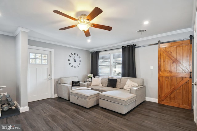 living room featuring a barn door, dark wood-type flooring, and ornamental molding