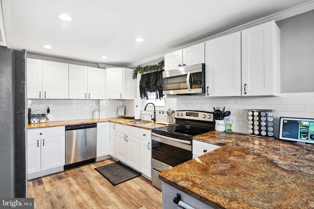 kitchen featuring white cabinets, appliances with stainless steel finishes, light wood-type flooring, and a sink