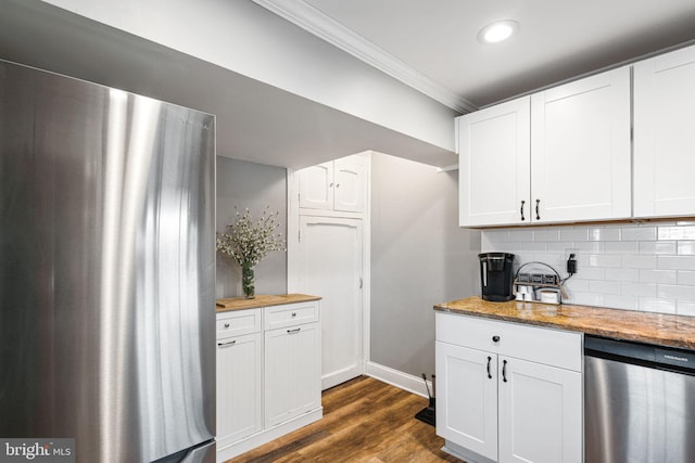 kitchen featuring dark wood-type flooring, appliances with stainless steel finishes, white cabinetry, crown molding, and backsplash