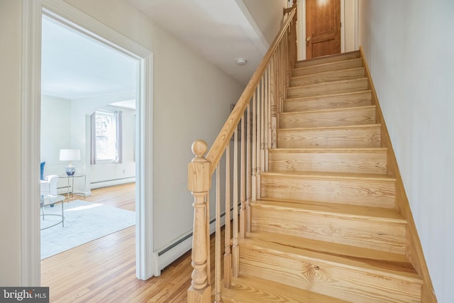 stairway with baseboard heating and wood finished floors