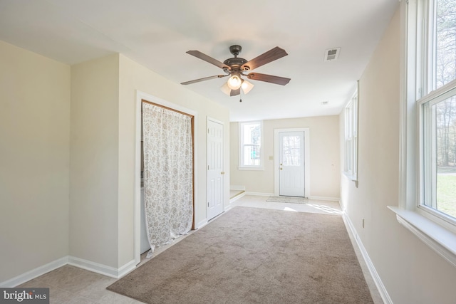 interior space with visible vents, ceiling fan, plenty of natural light, and baseboards