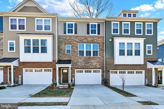 multi unit property featuring an attached garage, stone siding, and driveway