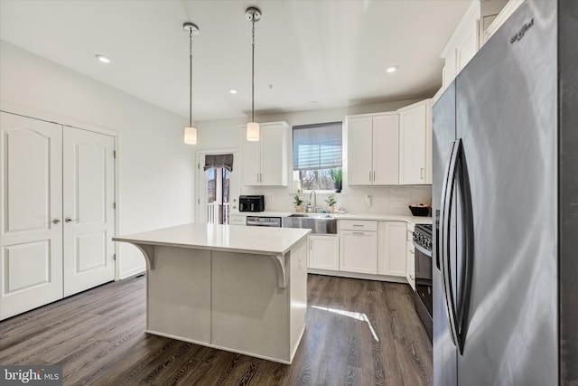 kitchen with appliances with stainless steel finishes, white cabinetry, light countertops, and dark wood-style flooring