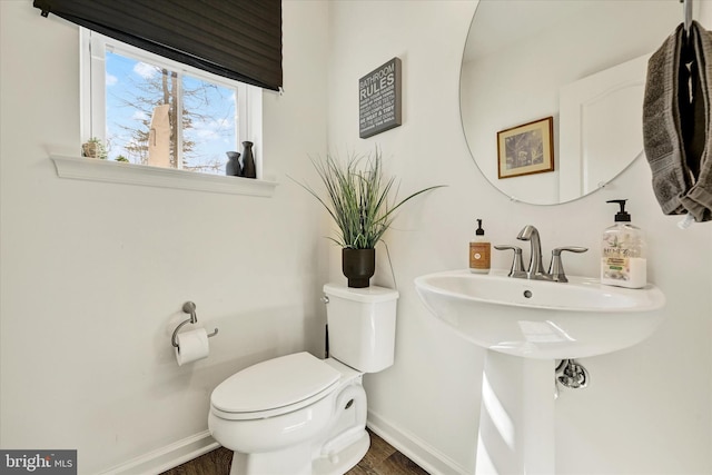 half bathroom featuring toilet, baseboards, and wood finished floors