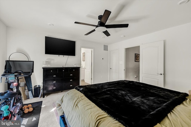 carpeted bedroom with visible vents, ensuite bath, and a ceiling fan