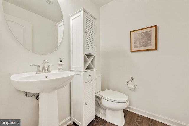 half bath featuring baseboards, toilet, and wood finished floors