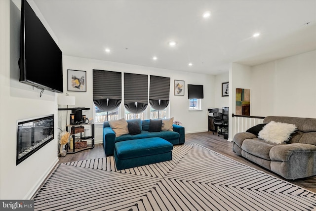 living room with a glass covered fireplace, recessed lighting, wood finished floors, and baseboards