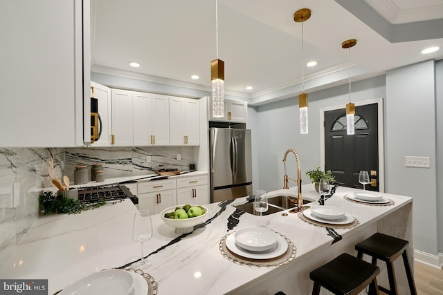 kitchen featuring a sink, decorative light fixtures, tasteful backsplash, freestanding refrigerator, and crown molding