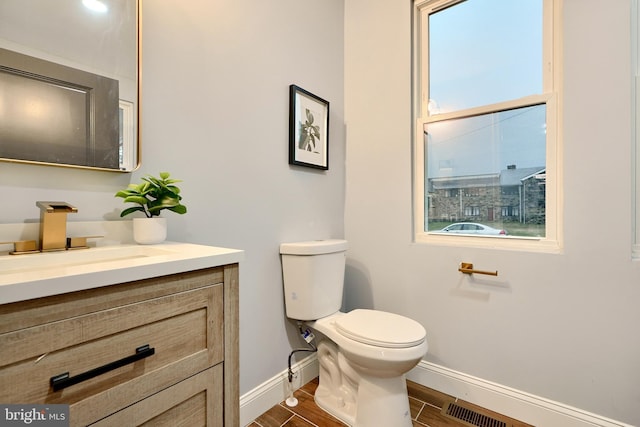 bathroom featuring visible vents, toilet, wood finished floors, baseboards, and vanity