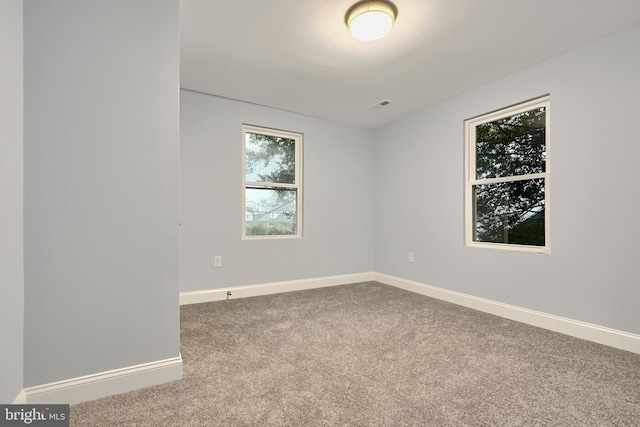 carpeted empty room featuring baseboards and visible vents