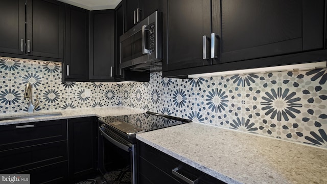 kitchen featuring decorative backsplash, stainless steel microwave, a sink, dark cabinetry, and black electric range