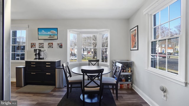 dining space featuring dark wood-type flooring and baseboards