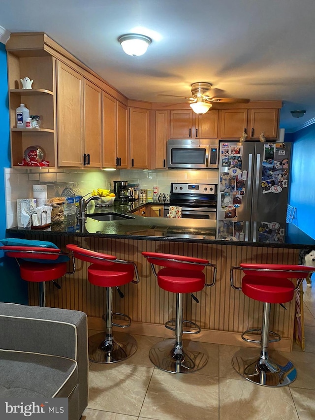 bar with backsplash, ceiling fan, appliances with stainless steel finishes, a bar, and a sink