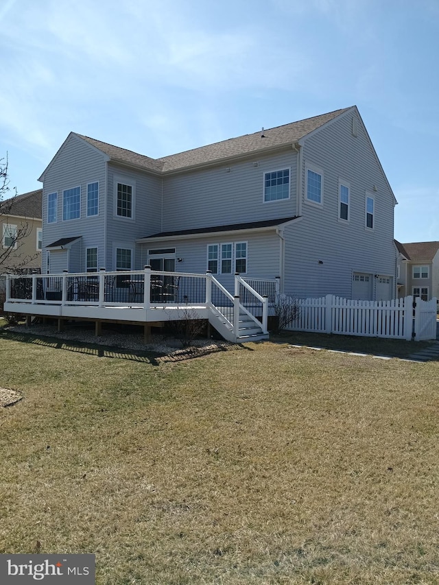 back of house with an attached garage, a wooden deck, a yard, and fence