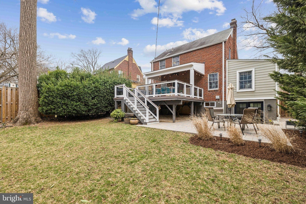 back of property featuring a patio, fence, a yard, a deck, and brick siding