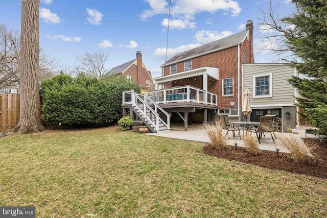 back of property featuring a patio, fence, a yard, a deck, and brick siding