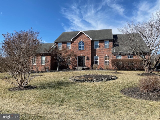 colonial home with brick siding and a front lawn