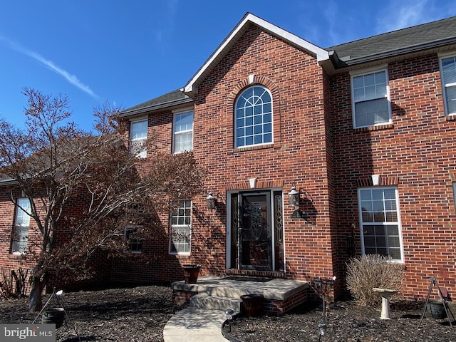 view of front of house featuring brick siding and roof with shingles