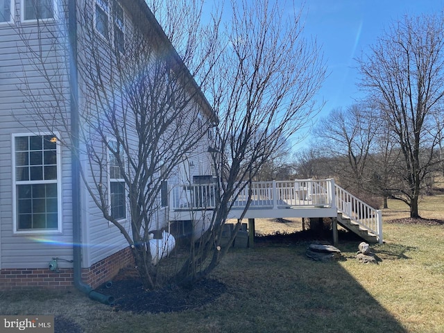 view of property exterior featuring a wooden deck, stairs, and a yard