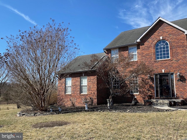 exterior space with brick siding and a lawn