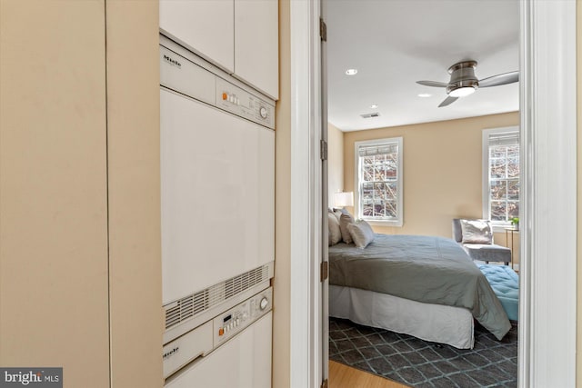 bedroom featuring stacked washer / dryer, visible vents, ceiling fan, recessed lighting, and wood finished floors