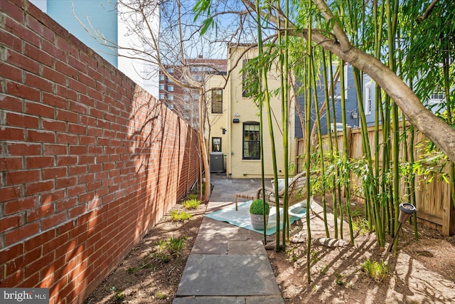 view of property exterior with a patio area, central AC, a fenced backyard, and brick siding