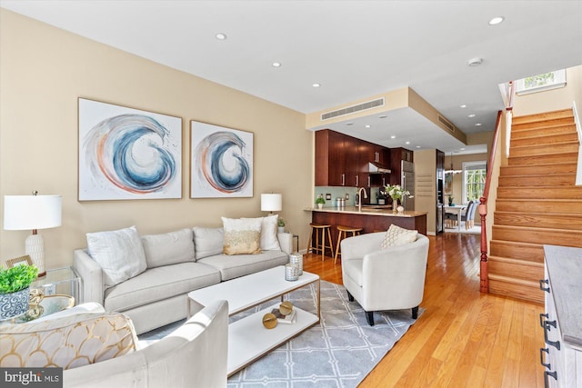 living area featuring light wood finished floors, visible vents, recessed lighting, and stairs