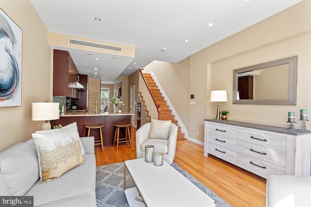 living area featuring visible vents, baseboards, stairs, recessed lighting, and light wood-style floors