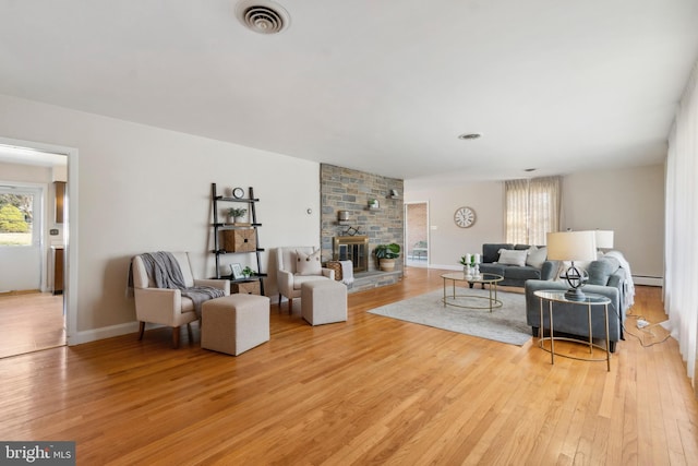 living area featuring light wood-style flooring, a healthy amount of sunlight, visible vents, and baseboard heating