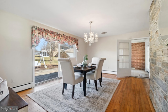 dining area with visible vents, a baseboard heating unit, an inviting chandelier, and hardwood / wood-style floors