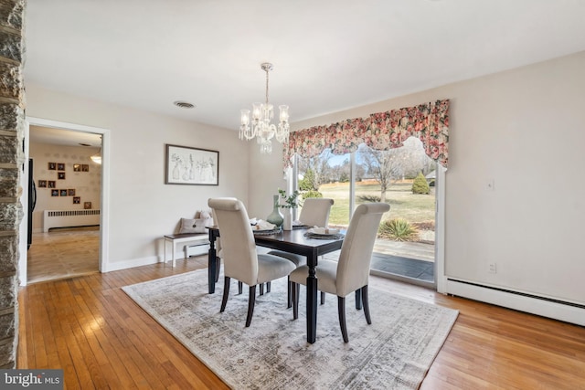 dining room with visible vents, a chandelier, radiator heating unit, wood-type flooring, and a baseboard radiator