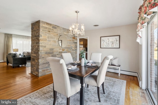 dining area featuring light wood finished floors, visible vents, and a notable chandelier