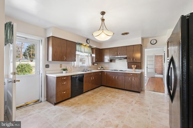 kitchen with under cabinet range hood, black appliances, light countertops, and a sink