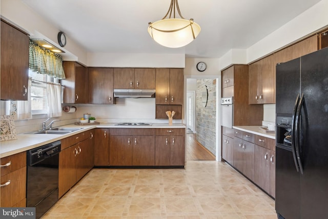 kitchen featuring under cabinet range hood, black appliances, light countertops, and a sink