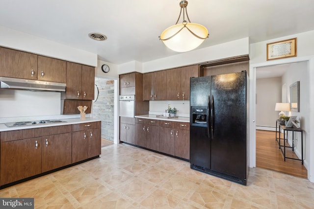 kitchen with oven, visible vents, electric cooktop, black fridge, and under cabinet range hood