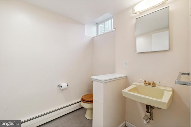 half bath featuring tile patterned flooring, a sink, toilet, and a baseboard radiator