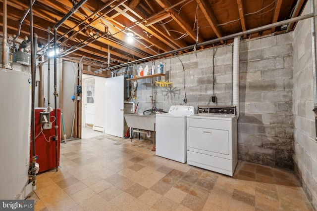 unfinished below grade area featuring washing machine and clothes dryer, water heater, a heating unit, a sink, and tile patterned floors