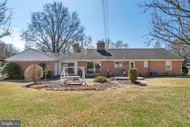 rear view of house with brick siding, a chimney, a lawn, and a patio area